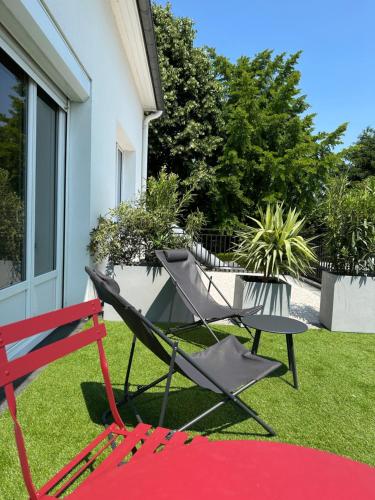 a red and black chair and a table in a yard at Logis Hôtel & Restaurant Le Vert Bocage in Franqueville-Saint-Pierre
