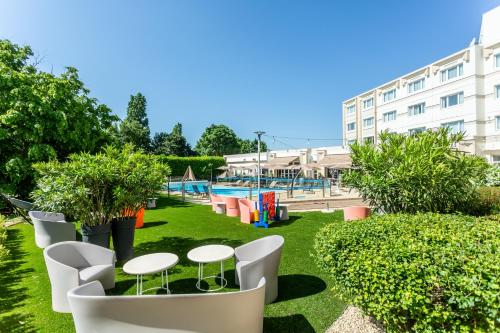 a park with tables and chairs in front of a building at Novotel Bourges in Bourges