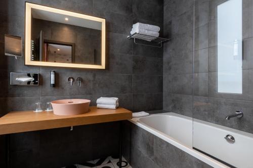 a bathroom with a sink and a tub and a mirror at Best Western Plus Monopole Métropole in Strasbourg