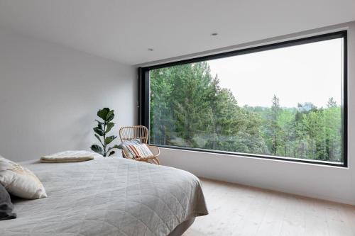 a bedroom with a large window with a bed and a chair at Swedish Elegance & Luxury Home in Stockholm