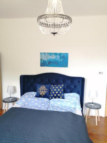 a bedroom with a blue bed and a chandelier at Ari Villa Révfülöp in Révfülöp