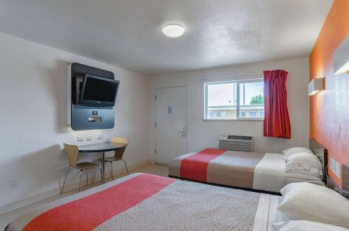 um quarto com uma cama, uma secretária e uma televisão em Motel 6 Riverton WY em Riverton