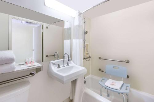 a white bathroom with a sink and a bath tub at Ramada Plaza by Wyndham Waikiki in Honolulu