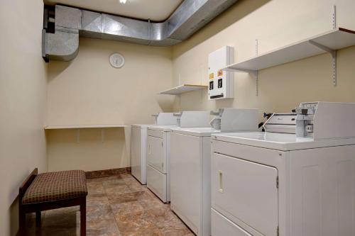 a kitchen with white cabinets and a stool in a room at Days Inn by Wyndham Dawson Creek in Dawson Creek
