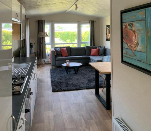 cocina y sala de estar con sofá y mesa en Chalet Rivendell, en Menaldum