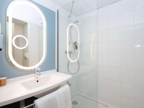 a white bathroom with a sink and a mirror at ibis Reims Tinqueux in Reims