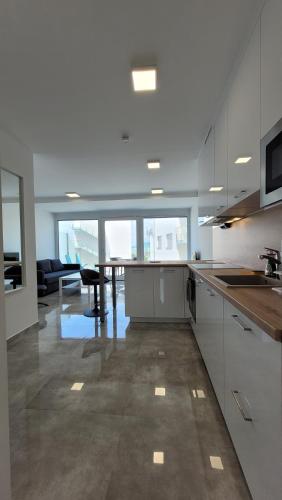 a kitchen with white cabinets and a table in it at Szabadszél Apartmanok in Fonyód