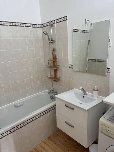 une salle de bain avec un lavabo, une baignoire et un miroir dans l'établissement la maison Haute, à Palluau-sur-Indre