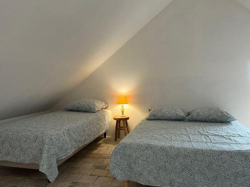 une chambre avec deux lits et une table avec une lampe dans l'établissement la maison Haute, à Palluau-sur-Indre