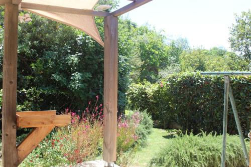 une pergola en bois au milieu d'un jardin dans l'établissement MINI VILLA PALOMBAGGIA - Piscine chauffée, à Porto-Vecchio