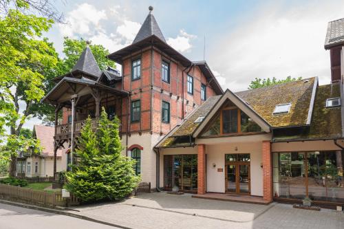 een groot bakstenen gebouw met een torentje bij Villa Bachmann - Kuršių kiemas in Juodkrantė