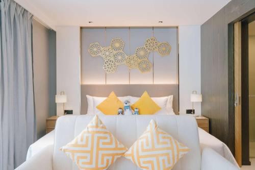 1 dormitorio con 1 cama blanca grande con almohadas amarillas en Wyndham La Vita Rawai Phuket, en Rawai Beach