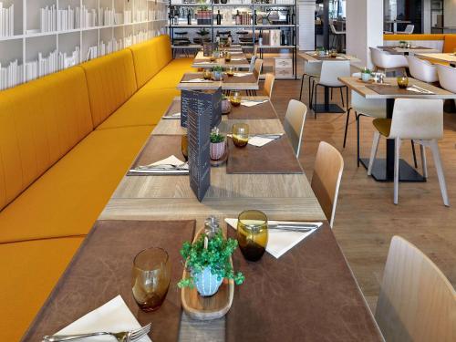 una fila de mesas en un restaurante con paredes amarillas en ibis Styles La Roche-sur-Yon, en Mouilleron-le-Captif