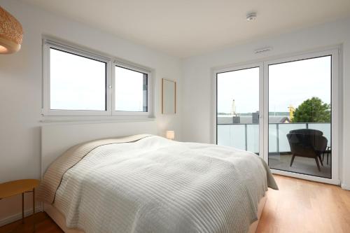 a white bedroom with a bed and two windows at Seaside in Laboe