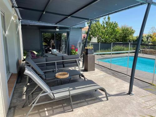 um pátio com uma mesa e cadeiras e uma piscina em petit paradis au soleil em Narbona