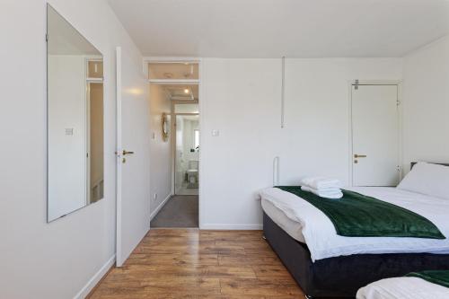 a bedroom with white walls and a bed with a green blanket at Comfortable Home in Kent, Sleeps 6 - Parking Available in Kent