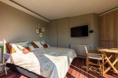 Schlafzimmer mit einem Bett, einem Tisch und einem TV in der Unterkunft Villa Francine in Deinze