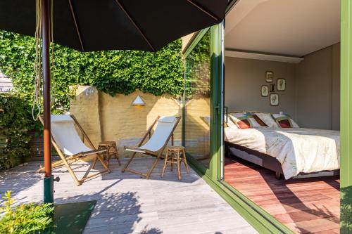 ein Schlafzimmer mit einem Bett, zwei Stühlen und einem Sonnenschirm in der Unterkunft Villa Francine in Deinze