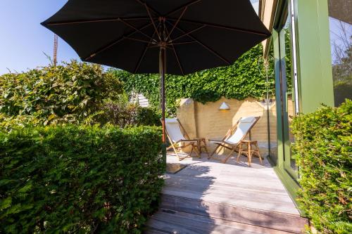 un patio con 2 sillas y una sombrilla en Villa Francine, en Deinze