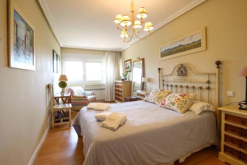 um quarto com uma cama grande e um lustre em Apartamento frente al Sardinero em Santander