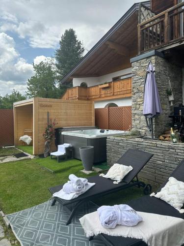a backyard with a hot tub and two tables and an umbrella at Stile Oase Apartment 1 in Bruck an der Großglocknerstraße