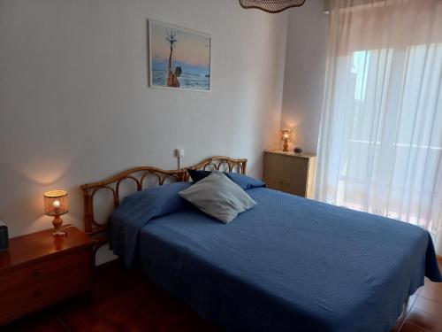 Un dormitorio con una cama azul y una ventana en Grazioso Bilocale Caletta Castiglioncello - Tuscany, en Castiglioncello