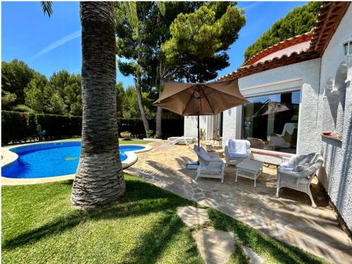 a patio with chairs and an umbrella next to a pool at ARENDA Villa Camila Pino Alto in Miami Platja