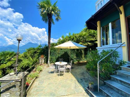 eine Terrasse mit einem Sonnenschirm, einem Tisch und Stühlen in der Unterkunft Villa Silvana in Perledo