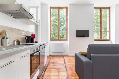- une cuisine avec des placards blancs et un canapé dans l'établissement Gambetta 302 CahorsCityStay, à Cahors
