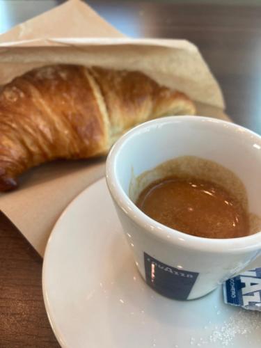 a plate with a cup of coffee and a croissant at JFK b & b in Ciampino