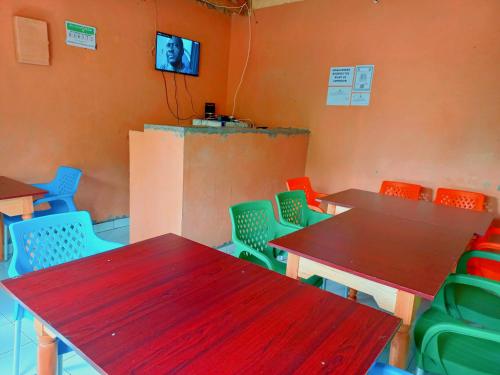 Habitación con mesas, sillas y TV. en Talanta Ajira Cottages en Kisumu