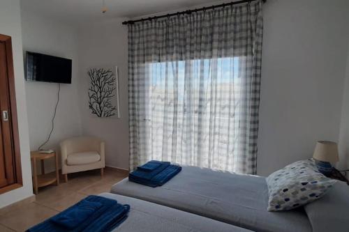a bedroom with a bed and a window with a chair at Villa Maracay-Caleta de Fuste-fiber optic 600mb in Caleta De Fuste