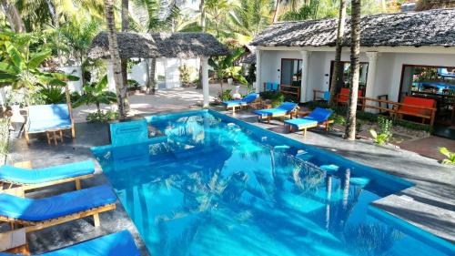 a pool with blue chairs and a house at little pompeji boutique hotel - adults only in Jambiani