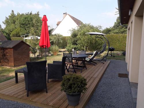 una terraza de madera con mesa, sillas y sombrilla en Home Relax Perche : gîte avec prestations bien-être en Montigny-le-Chartif