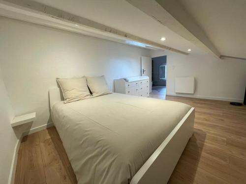 Cama blanca grande en habitación con suelo de madera en Duplex sous les toits, en Riez