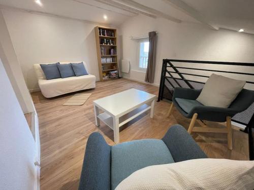 a living room with a couch and a table at Duplex sous les toits in Riez