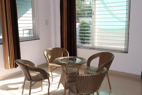 a table and chairs in a room with windows at Aashiyana Home Stay, Arera Colony, Bhopal in Bhopal