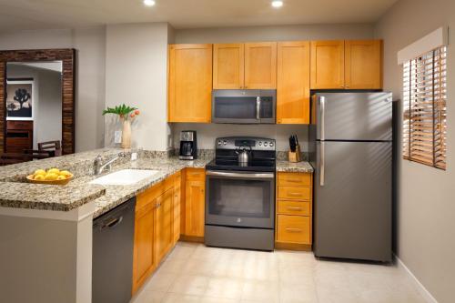 a kitchen with wooden cabinets and a stainless steel refrigerator at The Westin Mission Hills Resort Villas, Palm Springs in Rancho Mirage