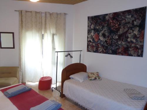 a bedroom with a bed and a window with a painting on the wall at Portuense Alojamento Local in Porto