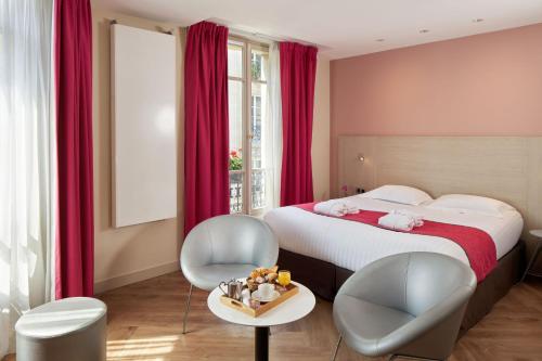 a bedroom with a bed and two chairs and a table at Hôtel de Sévigné in Paris