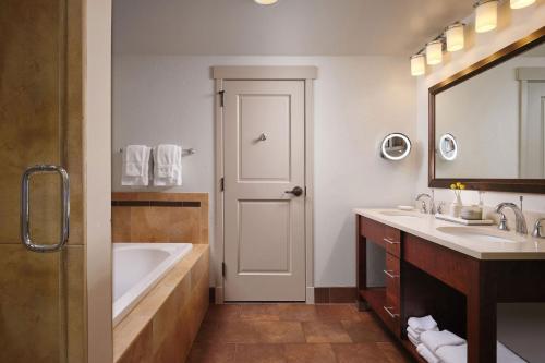 a bathroom with a tub and a sink and a mirror at Sheraton Steamboat Resort Villas in Steamboat Springs
