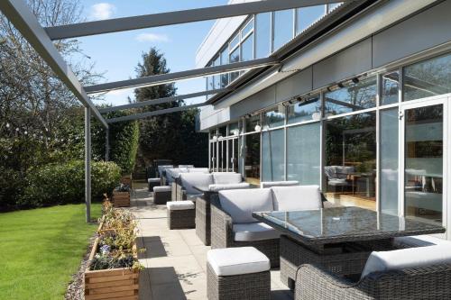 a patio with white chairs and tables and windows at Delta Hotels by Marriott Edinburgh in Edinburgh