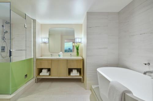 a bathroom with a tub and a sink and a mirror at Hotel Clio, a Luxury Collection Hotel, Denver Cherry Creek in Denver