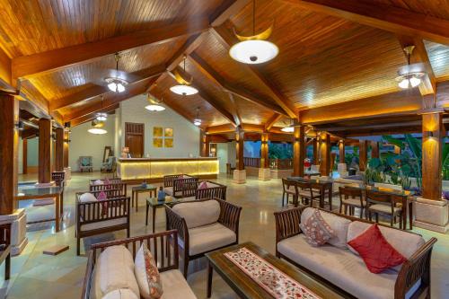 een lobby met houten plafonds en tafels en stoelen bij Riva Beach Resort in Mandrem