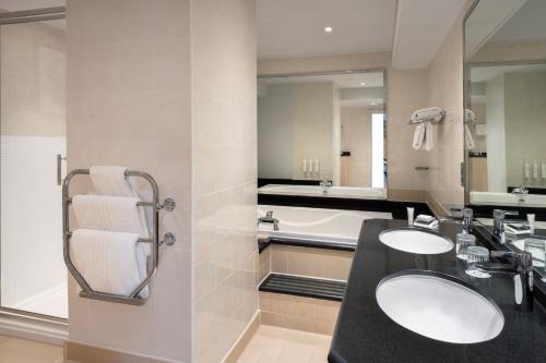 a bathroom with two sinks and a bath tub at Delta Hotels by Marriott Northampton in Northampton