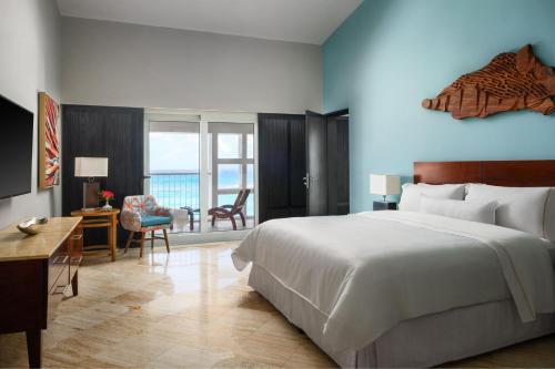 1 dormitorio con 1 cama blanca grande, escritorio y silla en The Westin Resort & Spa Cancun, en Cancún