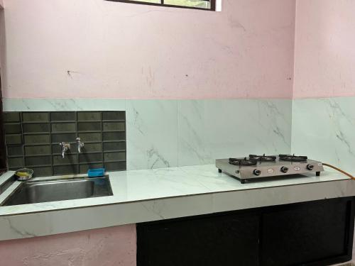 a kitchen counter with a stove and a sink at Sowparnika duplex in Trivandrum