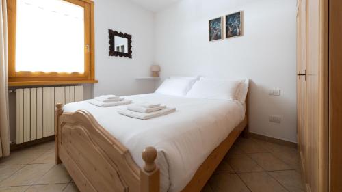 um quarto com uma cama com lençóis brancos e uma janela em Italianway - Mulino 5 em Valdisotto