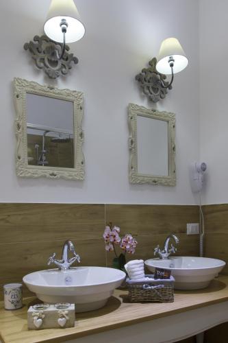 two sinks on a counter in a bathroom with mirrors at TAM Vacanze B&B in Cinisi