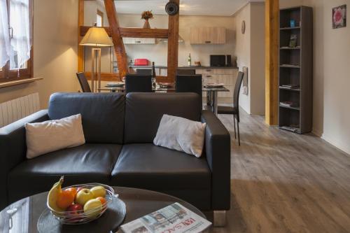 un salon avec un canapé et une table avec un bol de fruits dans l'établissement Gîte les Cigogneaux, à Turckheim